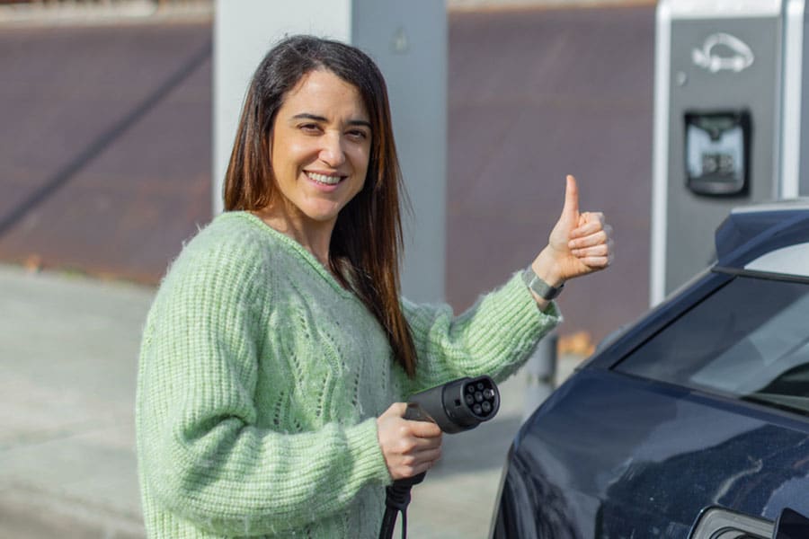 Une jeune femme qui a acheté une voiture électrique grâce au microcrédit véhicule propre